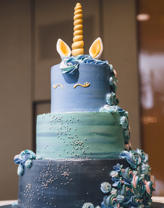 three-tier cake with a unicorn horn on top